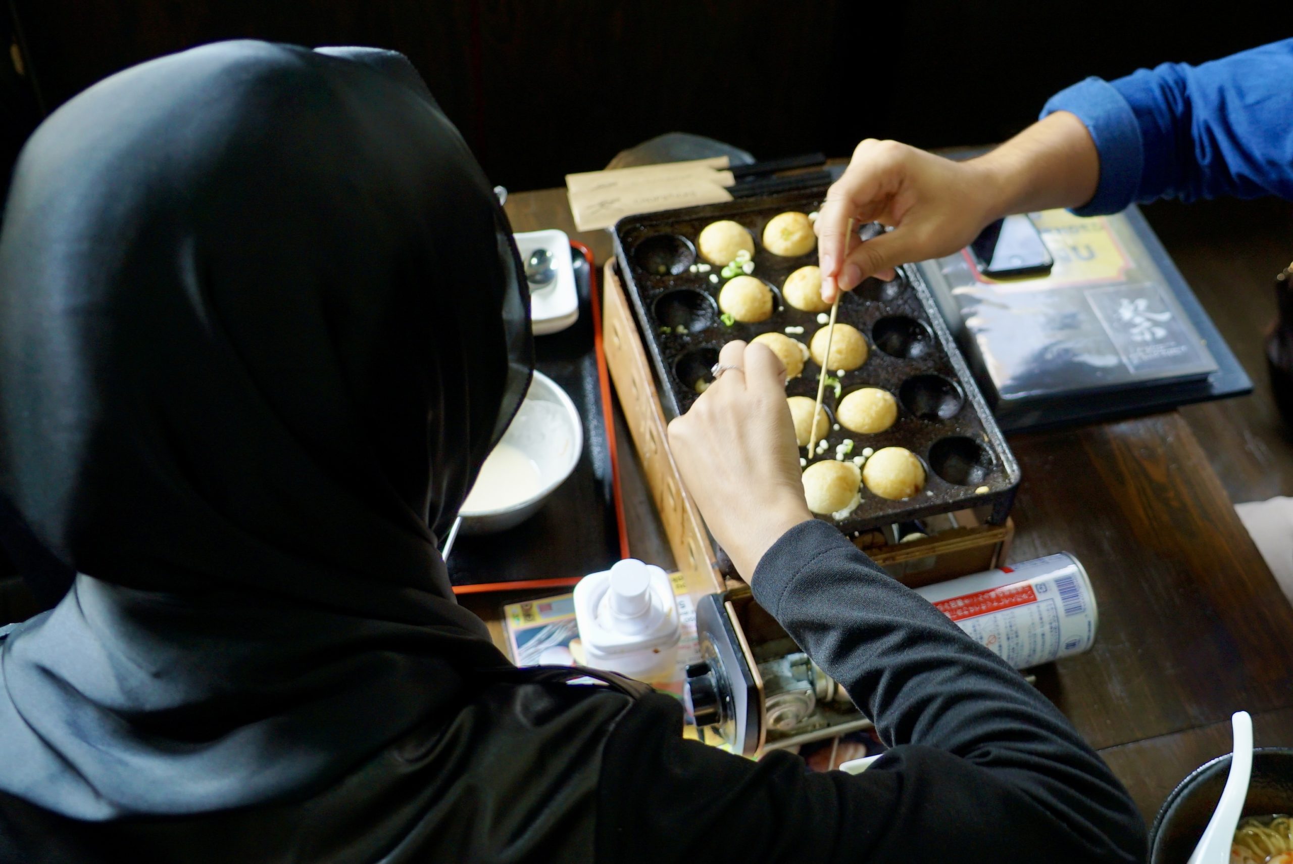 Customers making takoyaki by hand at Matsuri