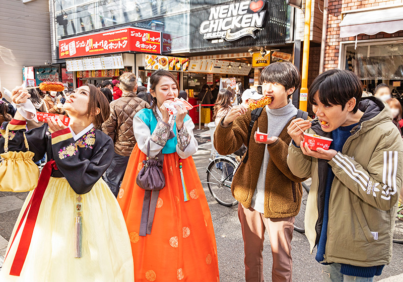 大阪鶴橋コリアタウンの韓国グルメ「ジョンノハットグ」を食べるチマチョゴリを着た女性
