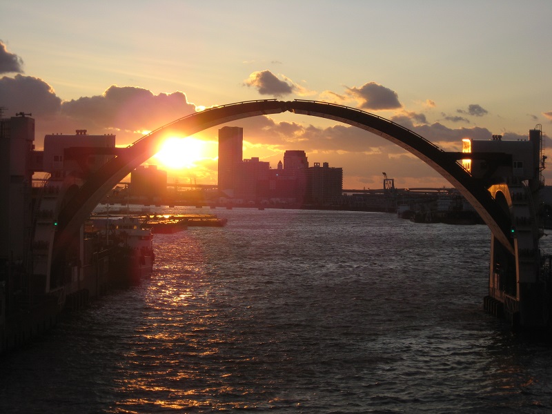 アーチ型の安治川水門の向こうに夕日が沈む