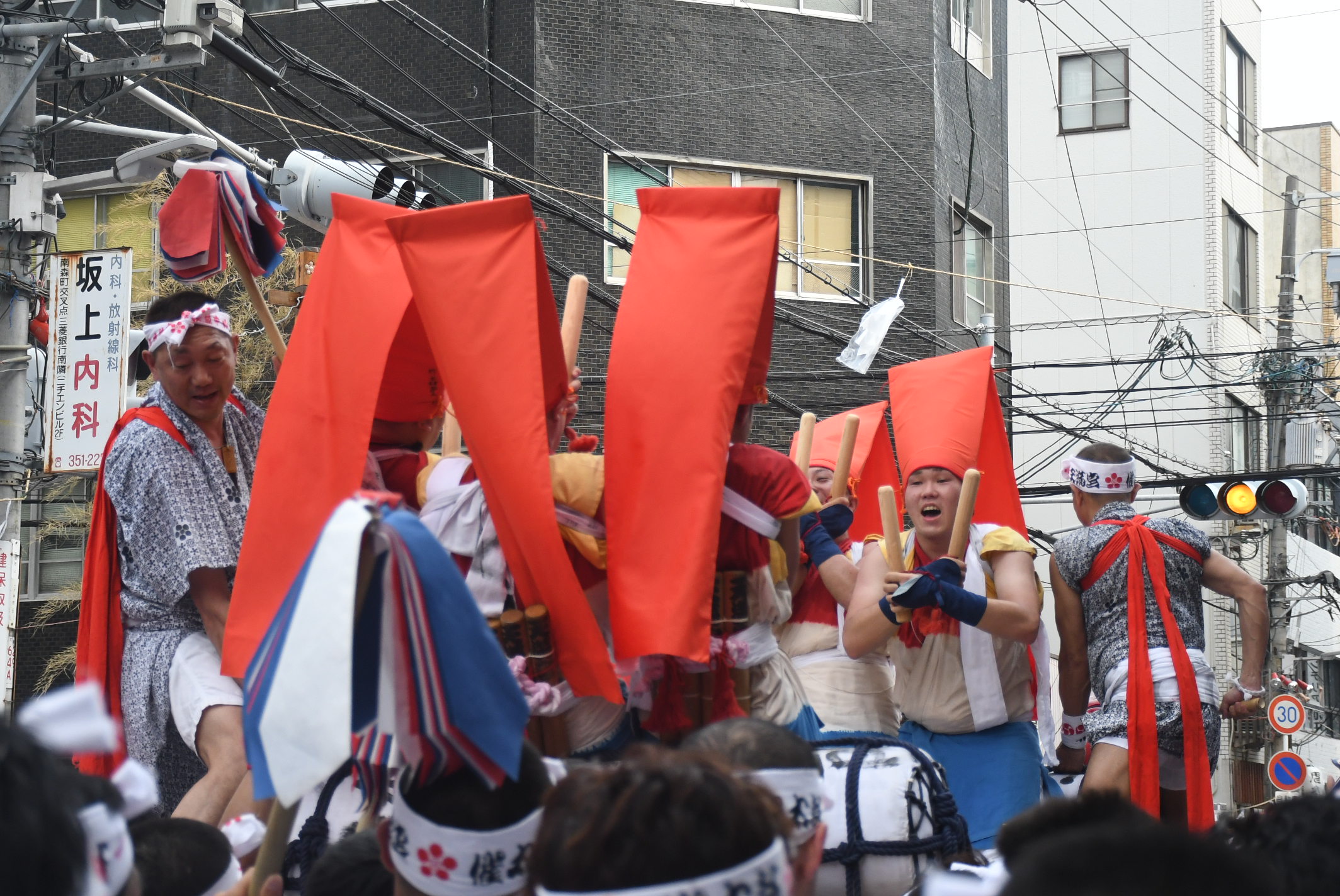 men in red hats on taiko platform being carried on platform during Tenjin Festival