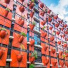 Organic Building facade, covered in plant pots protruding from red walls in Minami Semba