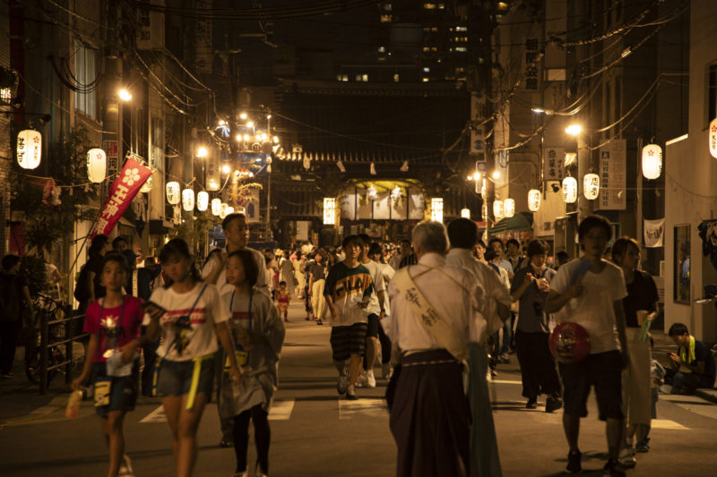 people returning home after last night of Tenjin Matsuri festival with lanterns lining the street