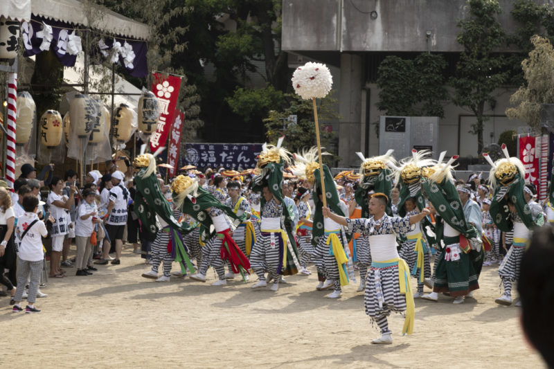 shishimai lion dance at Osaka Tenmangu, dancers draped in green robes carry a gold lion mask over their heads in unison