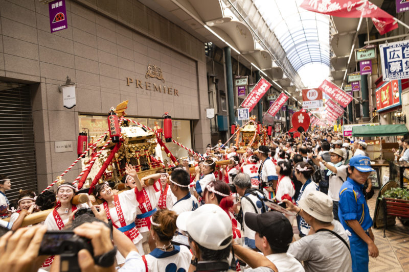 gal mikoshi in Tenjinbashisuji Shopping arcade, young women in festival costume carry golden portable shrine for Tenjin Matsuri