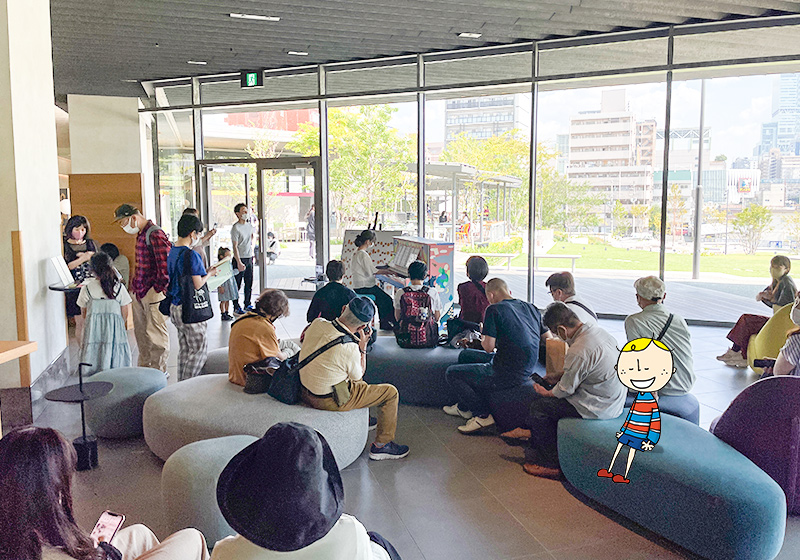 OMO７大阪by 星野リゾートのOMOベースに設置された「旅するLovePiano」の演奏に耳を傾ける宿泊客