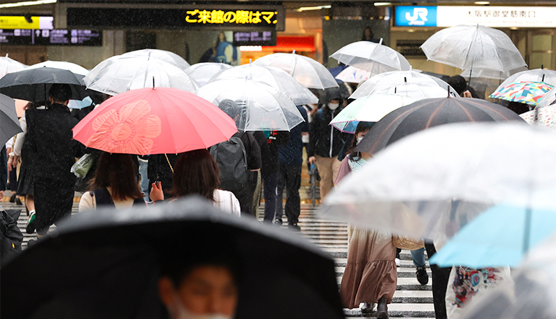 pedestrians carrying umbrellas on a rainy day at JR Osaka Station