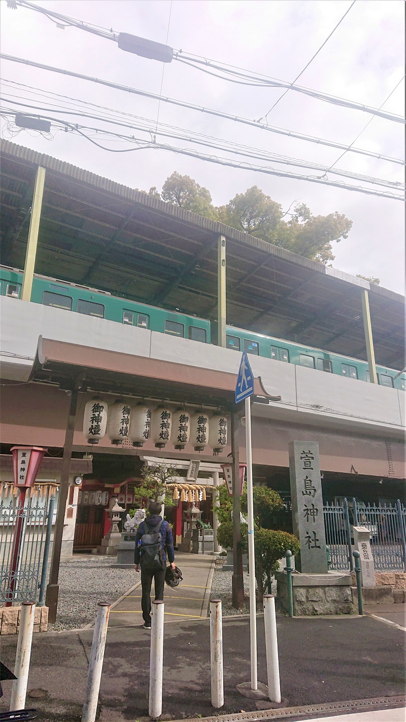 京阪萱島駅の高架下にある萱島神社。右上はホーム屋根から突き出た御神木