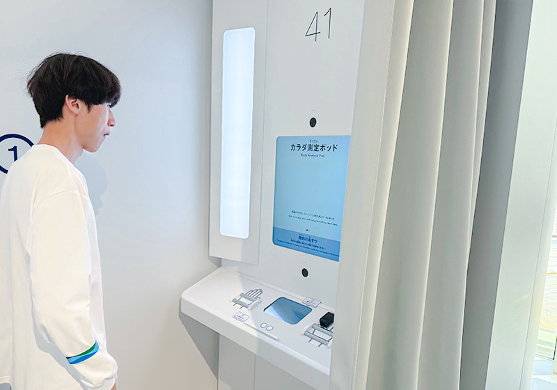 カラダ測定ポッドで健康データを取得するシーン