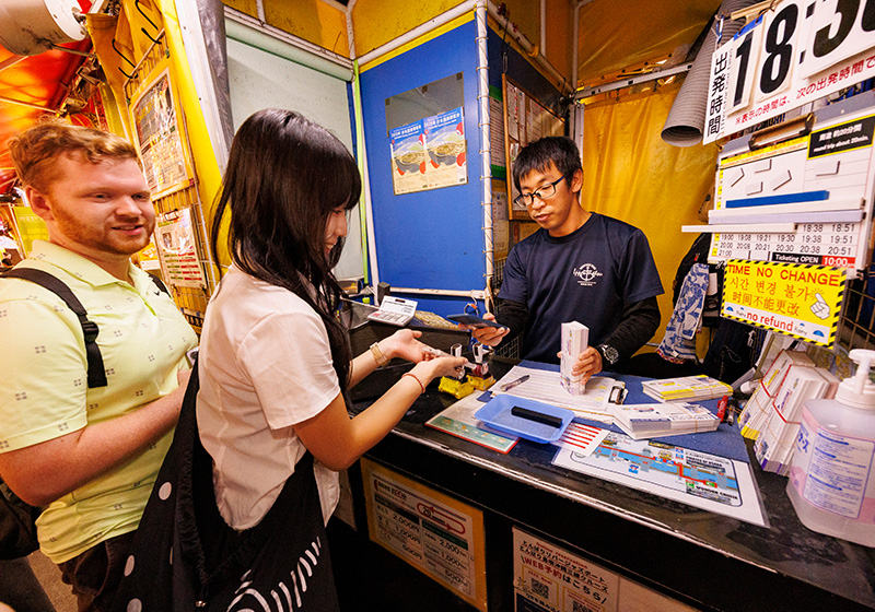 とんぼりリバークルーズの受付で大阪楽遊パスを提示する様子